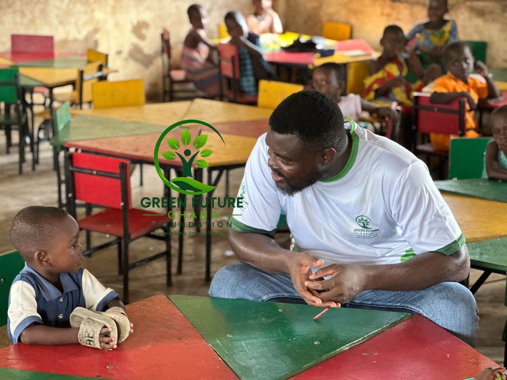 A foundation volunteer talking with a young pupil at his desk