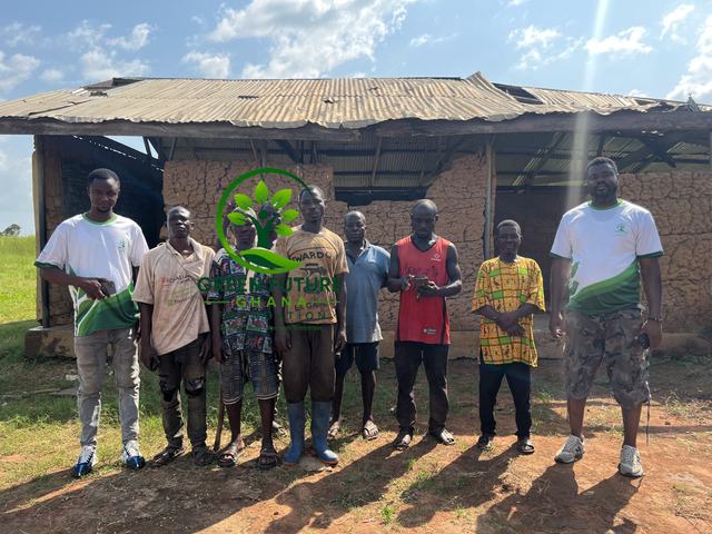 Foundation team members standing in front of a school building with a damaged roof