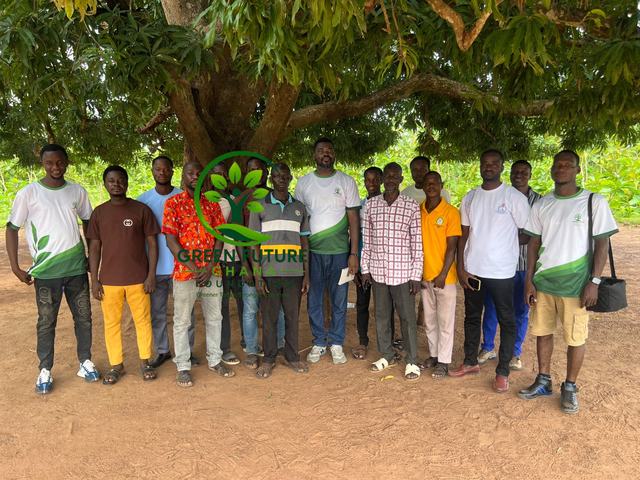 Foundation volunteers in their white and green shirts, gathered under a large tree